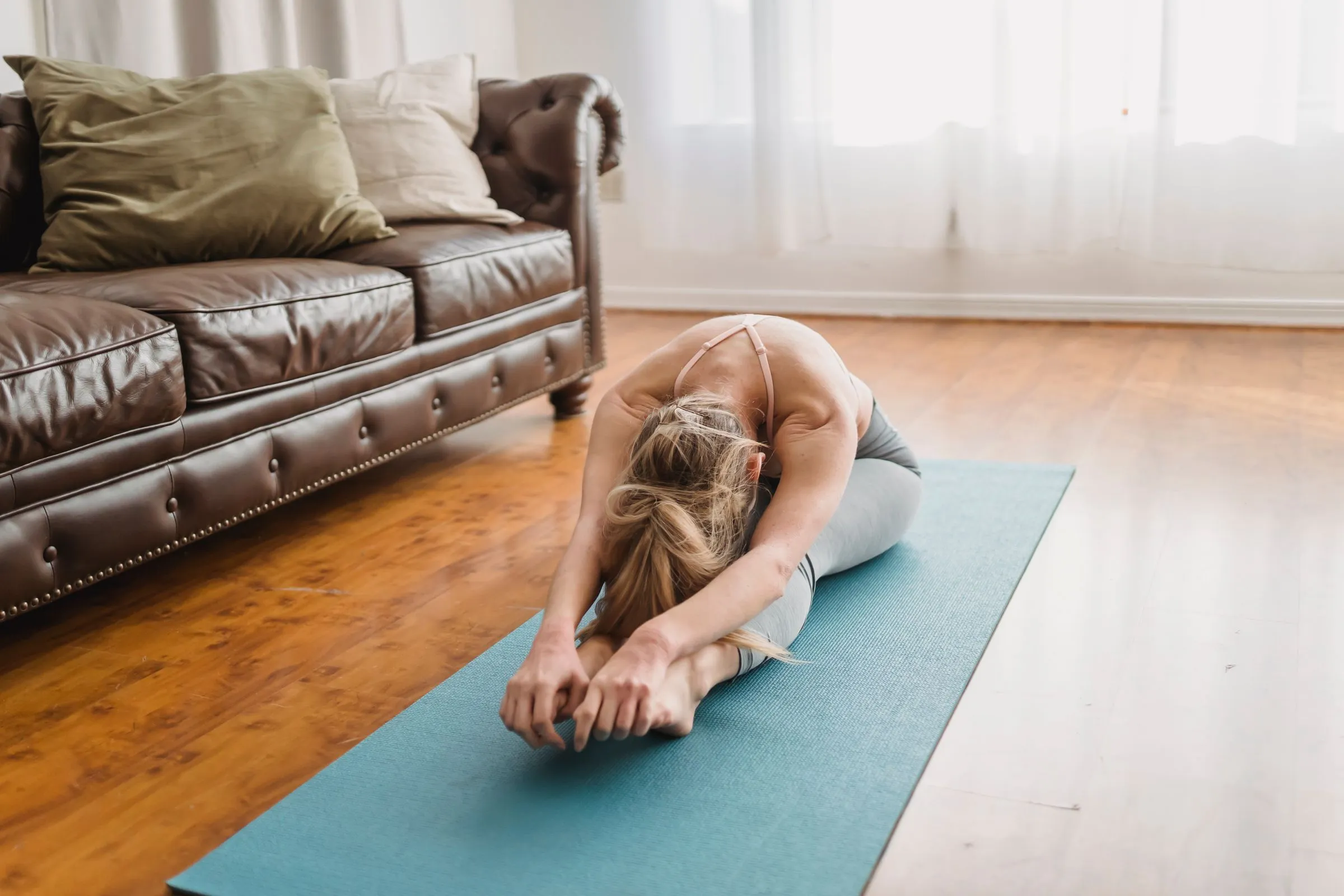 Dona practicant un estirament de pilates a terra en un espai lluminós