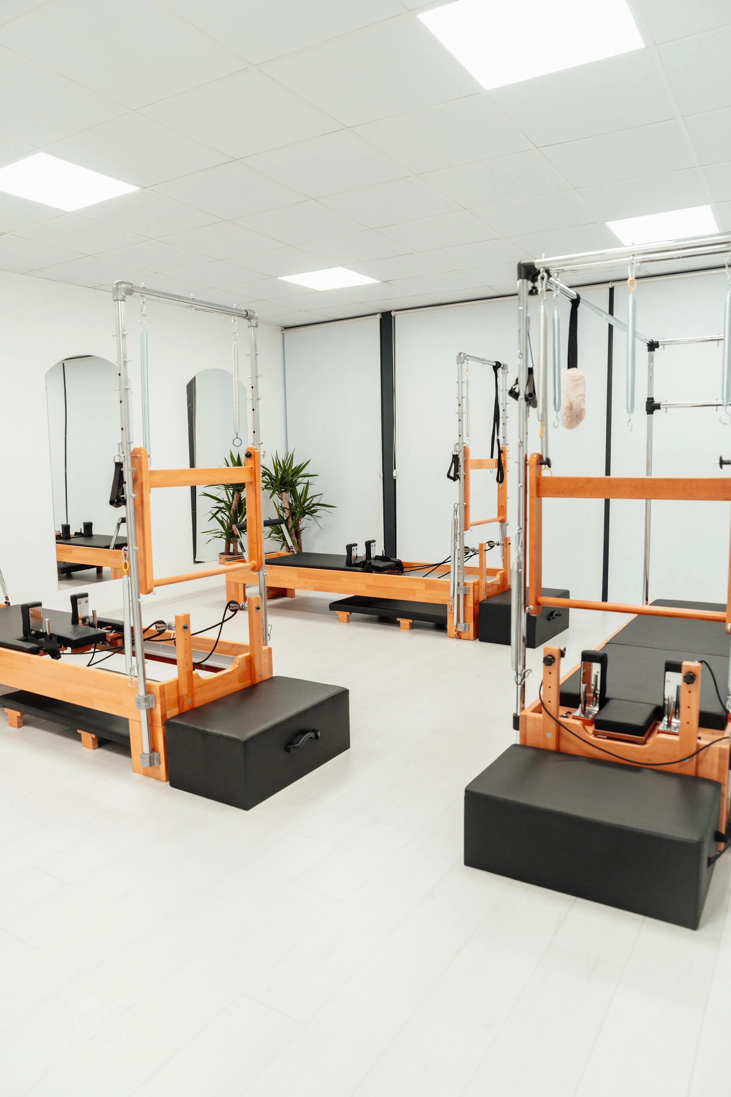 Estudi de pilates reformer blanc i lluminós amb màquines de fusta